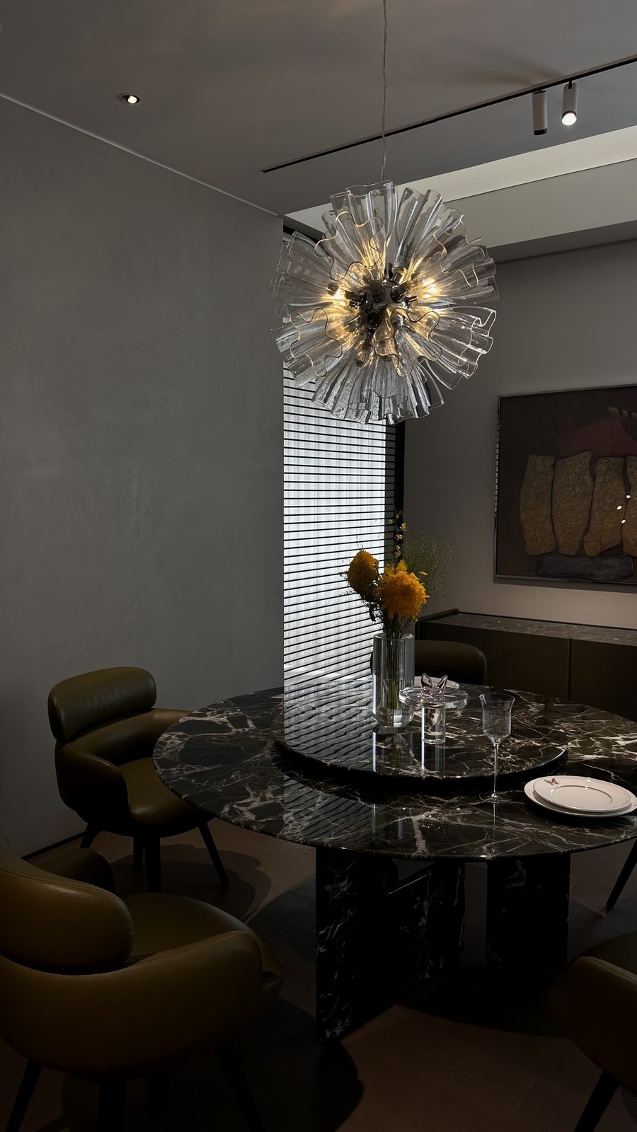Dining room with a marble table, leather chairs and a glass chandelier