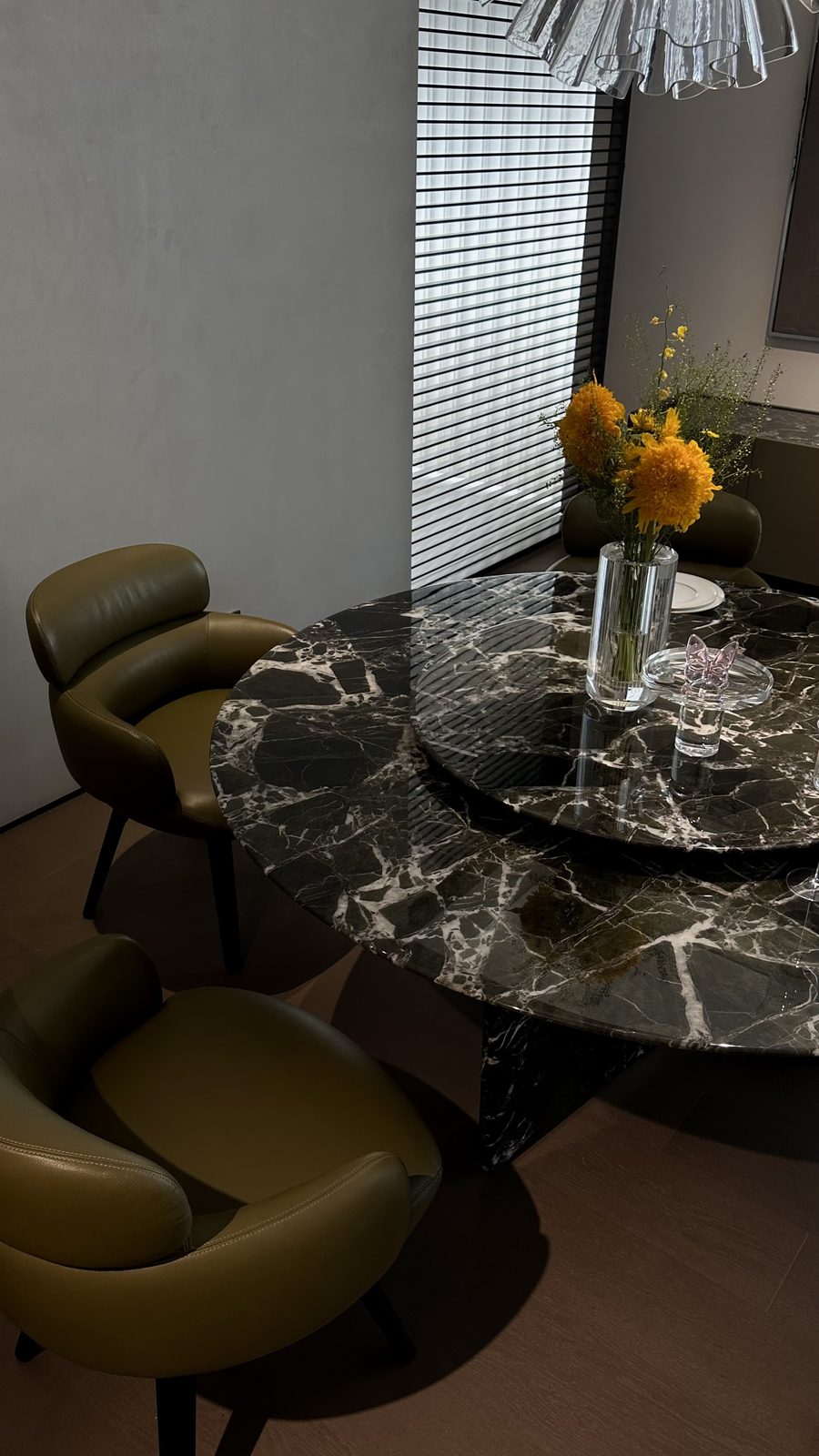 Round marble dining table with olive leather chairs in a furniture showroom